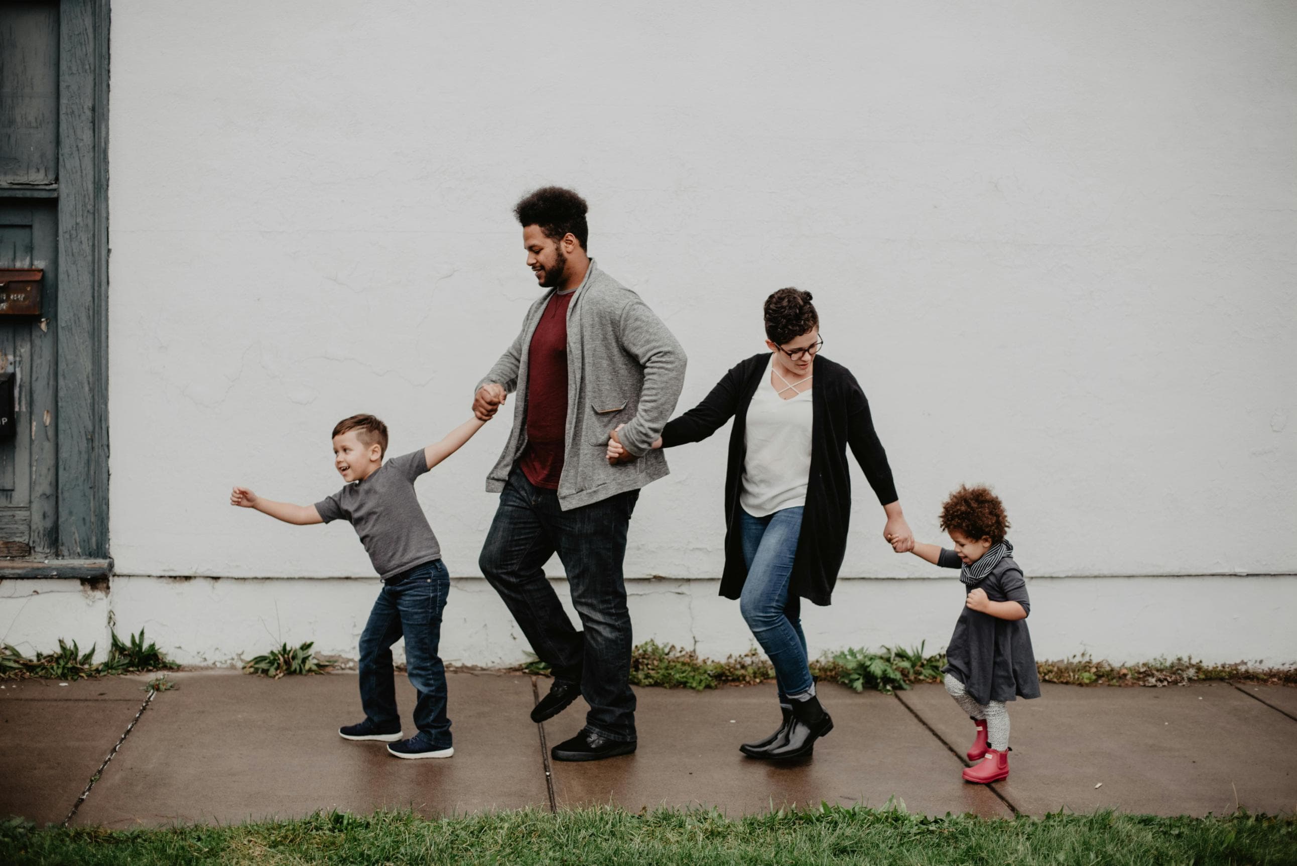 A family walking hand in hand down the sidewalk